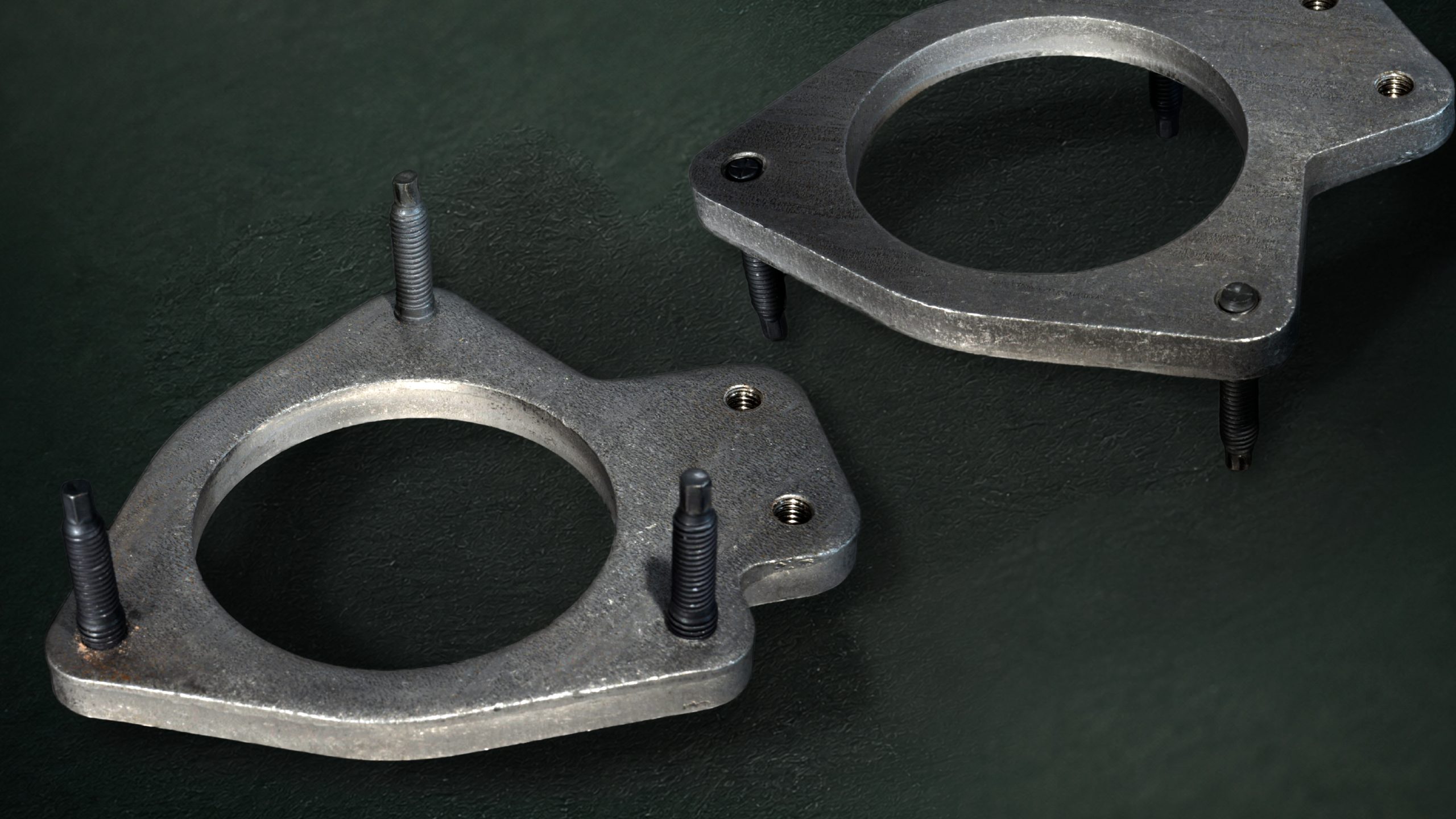 Close-up of two gray metal flange plates with threaded bolts on a dark green textured background.