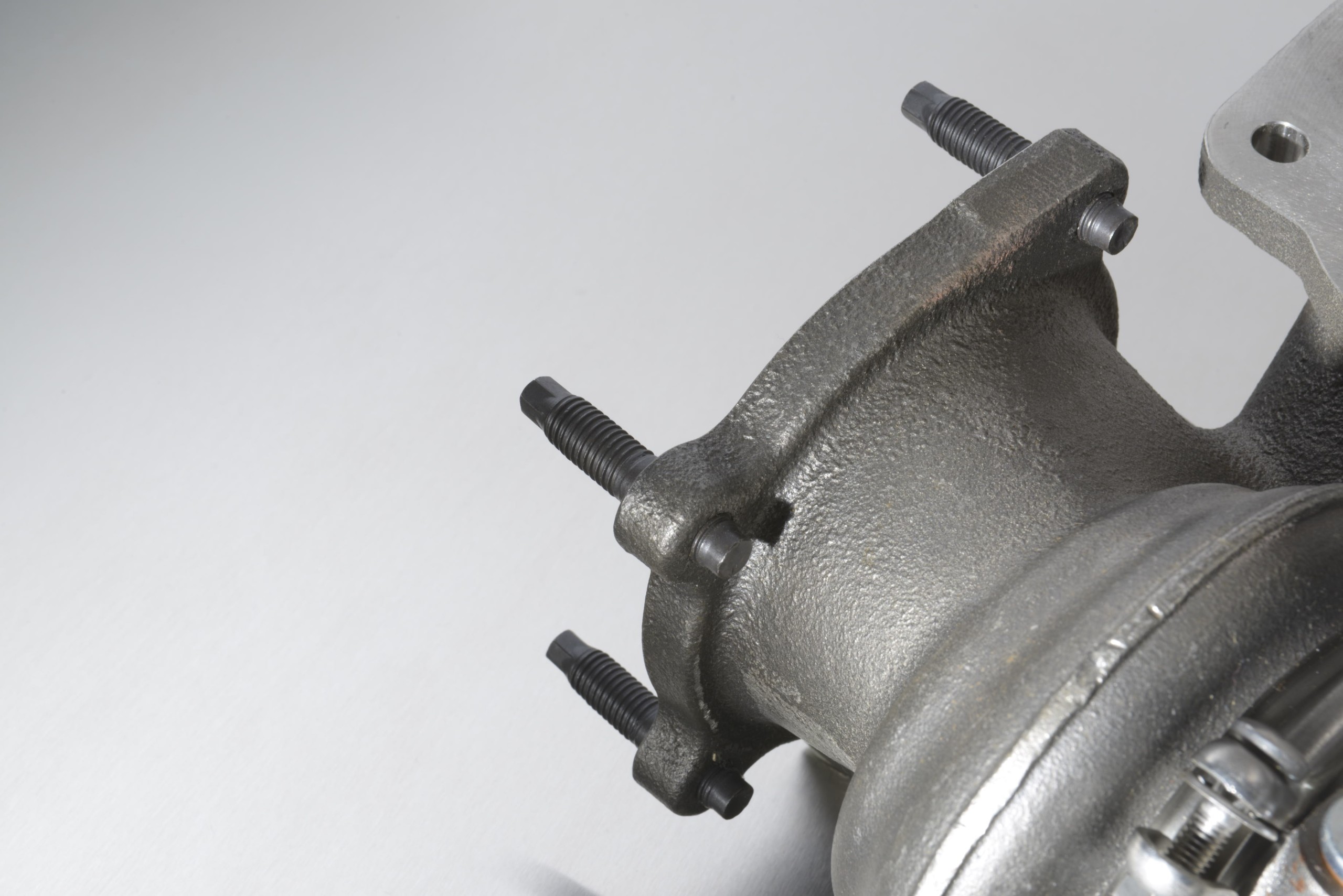 Close-up of a rugged metal clamp or bracket with threaded bolts protruding from a curved surface.